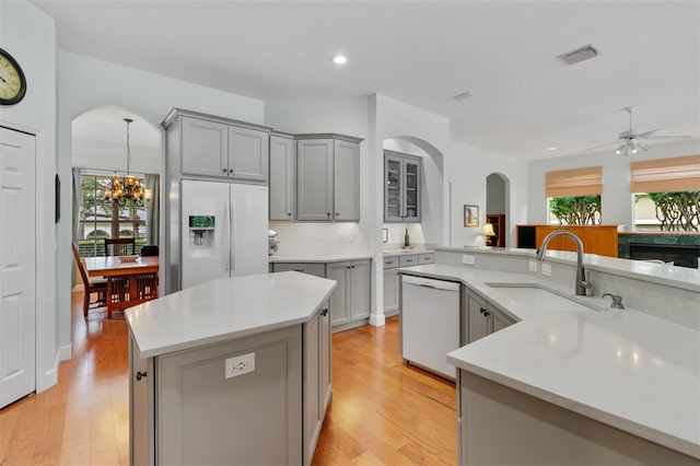 3372 Bellington Dr, Orlando, FL 32835 - kitchen with white appliances, gray cabinets, arched walkways, a kitchen island, and a sink