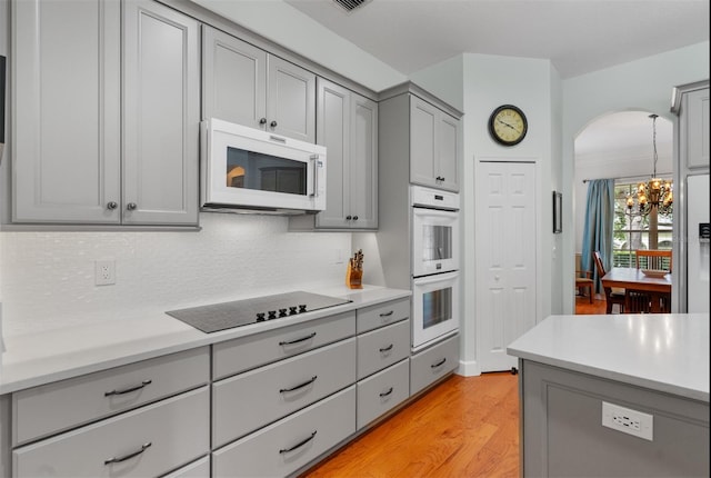 3372 Bellington Dr, Orlando, FL 32835 - kitchen with gray cabinets, white appliances, a chandelier, decorative backsplash, and light countertops