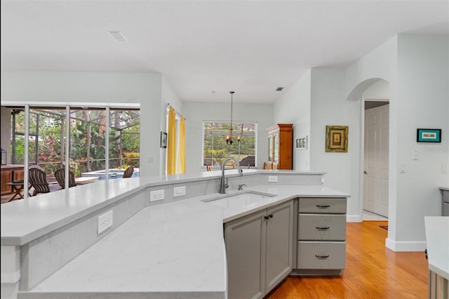 3372 Bellington Dr, Orlando, FL 32835 - kitchen with a sink, gray cabinets, light wood-style floors, a chandelier, and arched walkways