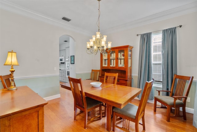 3372 Bellington Dr, Orlando, FL 32835 - dining area with arched walkways, a chandelier, ornamental molding, light wood finished floors, and baseboards