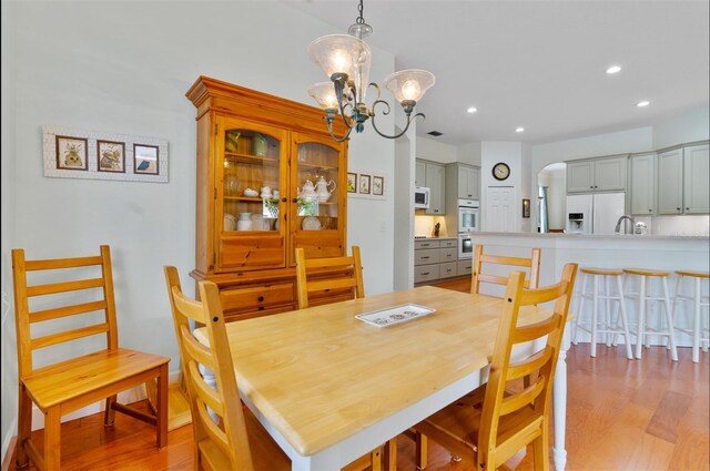 3372 Bellington Dr, Orlando, FL 32835 - dining area featuring light wood finished floors, a chandelier, arched walkways, and recessed lighting