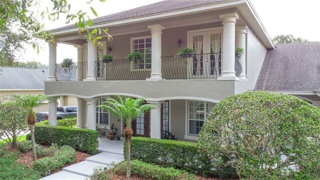 3372 Bellington Dr, Orlando, FL 32835 - view of front of home featuring a balcony, stucco siding, french doors, and roof with shingles