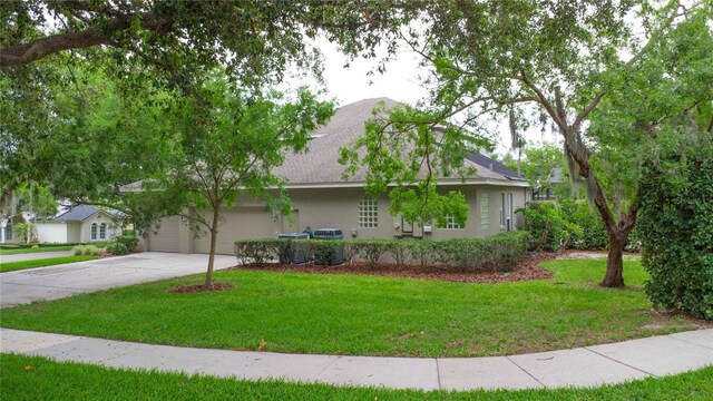 3372 Bellington Dr, Orlando, FL 32835 - view of front of home featuring concrete driveway, stucco siding, a front yard, a garage, and a shingled roof