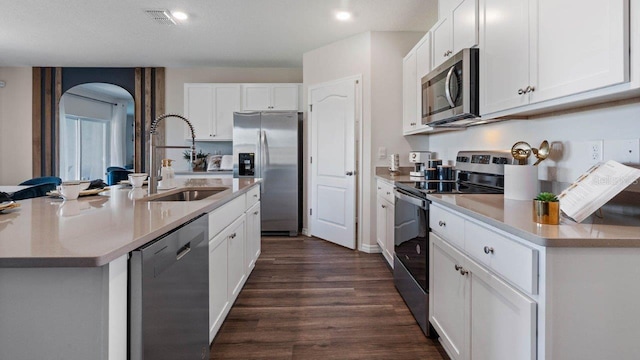 3141 Partington Blvd, Davenport, FL 33837 - kitchen featuring appliances with stainless steel finishes, a sink, arched walkways, dark wood-style floors, and white cabinets