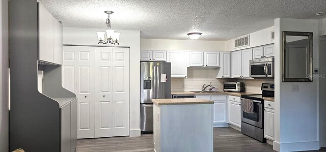 320 Forestway Cir Unit 107, Altamonte Springs, FL 32701 - kitchen featuring appliances with stainless steel finishes, wood finished floors, a chandelier, decorative backsplash, and a center island