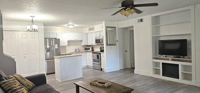 320 Forestway Cir Unit 107, Altamonte Springs, FL 32701 - living room with a ceiling fan, light wood finished floors, a chandelier, a textured ceiling, and built in shelves