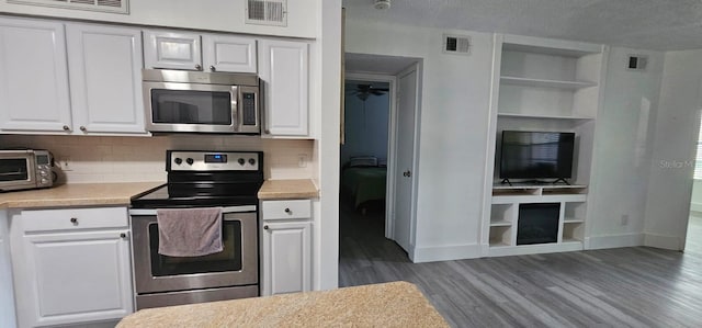 320 Forestway Cir Unit 107, Altamonte Springs, FL 32701 - kitchen with appliances with stainless steel finishes, wood finished floors, light countertops, white cabinets, and decorative backsplash