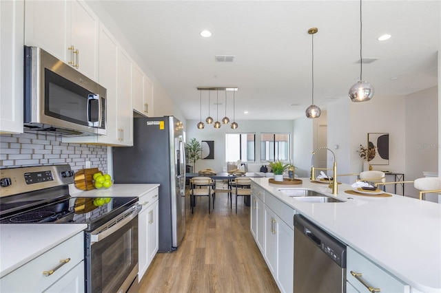 52 W Harding St Unit A, Orlando, FL 32806 - kitchen with appliances with stainless steel finishes, a sink, light countertops, white cabinetry, and light wood-style floors
