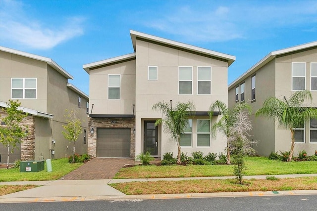 9239 Sommerset Hills Dr, Davenport, FL 33896 - modern home featuring an attached garage, decorative driveway, stucco siding, stone siding, and a front lawn