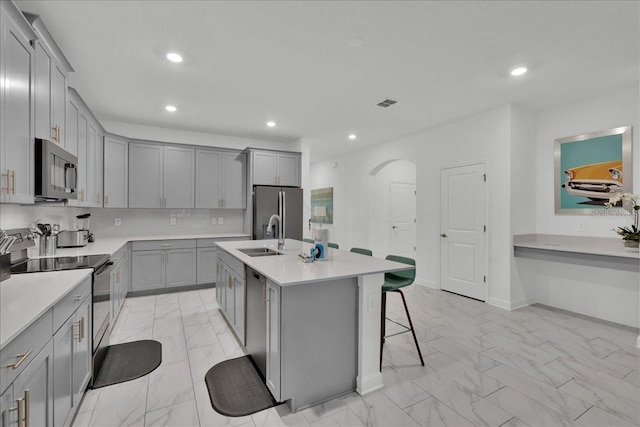9239 Sommerset Hills Dr, Davenport, FL 33896 - kitchen featuring stainless steel appliances, gray cabinets, light marble finish floors, arched walkways, and a sink