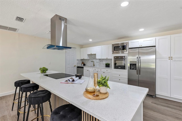 822 Glen Arden Way, Altamonte Springs, FL 32701 - kitchen featuring stainless steel appliances, island range hood, light wood finished floors, white cabinetry, and a breakfast bar area
