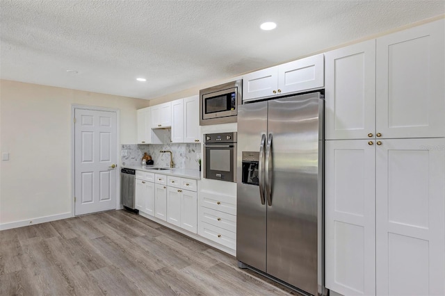 822 Glen Arden Way, Altamonte Springs, FL 32701 - kitchen with appliances with stainless steel finishes, a sink, a textured ceiling, light wood-type flooring, and white cabinetry