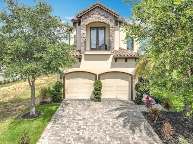 16246 Ravenna Ct, Montverde, FL 34756 - mediterranean / spanish house featuring a balcony, a tiled roof, stucco siding, french doors, and decorative driveway