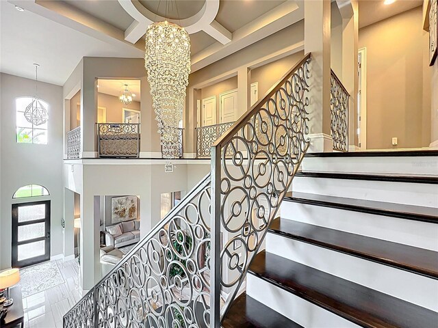 16246 Ravenna Ct, Montverde, FL 34756 - staircase featuring a chandelier, a towering ceiling, and coffered ceiling