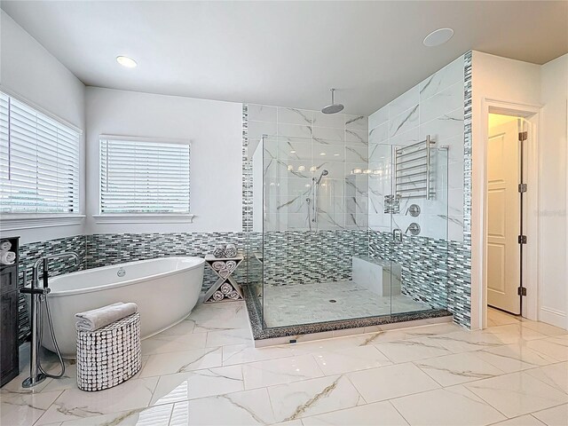 16246 Ravenna Ct, Montverde, FL 34756 - full bathroom featuring marble look tiles, a shower stall, a freestanding tub, recessed lighting, and wainscoting