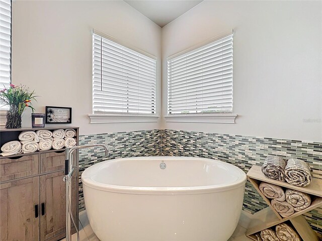16246 Ravenna Ct, Montverde, FL 34756 - full bath featuring tile walls, a freestanding bath, a wainscoted wall, and tile patterned floors