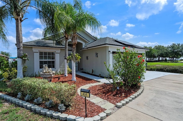 404 Obo Dr, Davenport, FL 33896 - view of front facade with stucco siding, concrete driveway, roof with shingles, and roof mounted solar panels