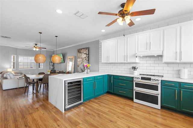 17404 Chateau Pine Way, Clermont, FL 34711 - kitchen with range with two ovens, a ceiling fan, beverage cooler, open floor plan, and crown molding