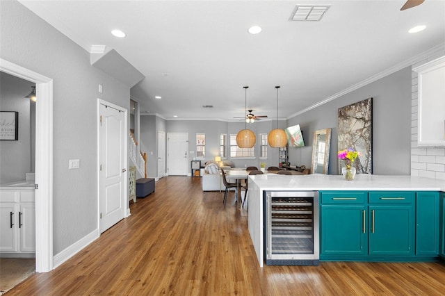 17404 Chateau Pine Way, Clermont, FL 34711 - kitchen featuring wine cooler, a ceiling fan, a peninsula, ornamental molding, and light countertops