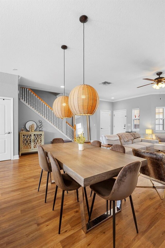 17404 Chateau Pine Way, Clermont, FL 34711 - dining area featuring stairway, ceiling fan, light wood-style floors, a textured ceiling, and crown molding