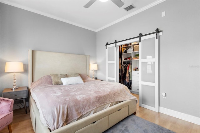 17404 Chateau Pine Way, Clermont, FL 34711 - bedroom with crown molding, wood finished floors, a barn door, a spacious closet, and a closet