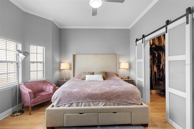 17404 Chateau Pine Way, Clermont, FL 34711 - bedroom featuring a barn door, light wood finished floors, a walk in closet, ornamental molding, and a closet