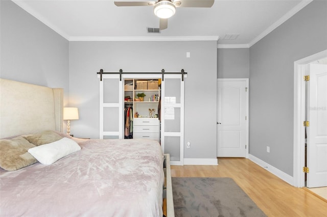 17404 Chateau Pine Way, Clermont, FL 34711 - bedroom featuring wood finished floors, ornamental molding, a barn door, a walk in closet, and baseboards