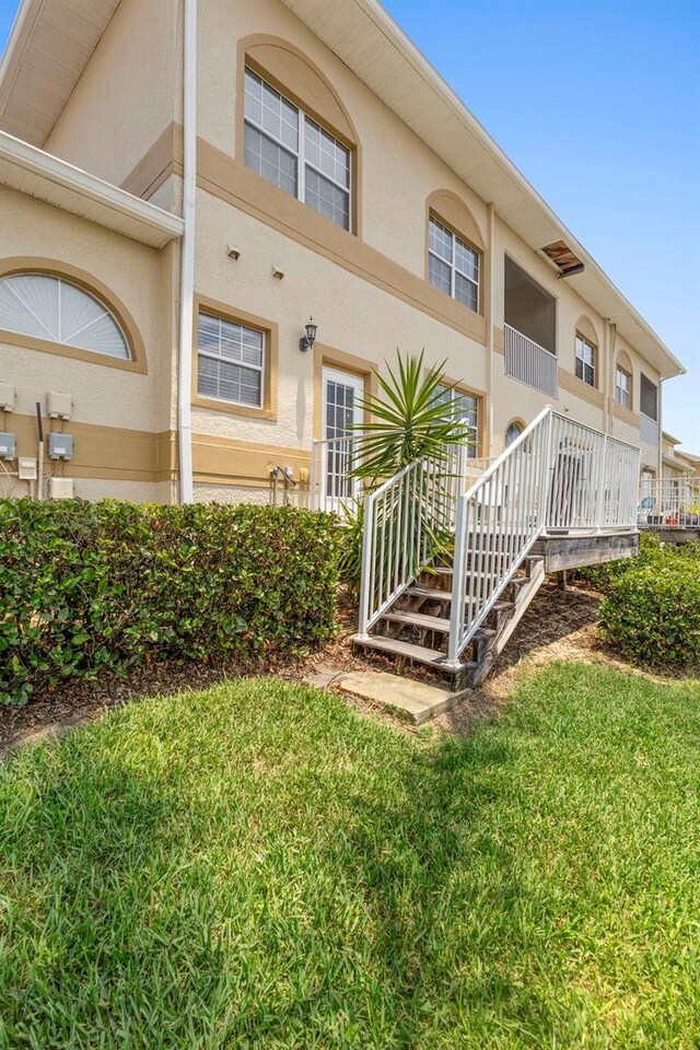 17404 Chateau Pine Way, Clermont, FL 34711 - rear view of property with stucco siding, a lawn, and stairs