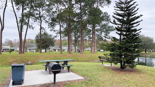 view of property's community with a yard, a patio, and a water view