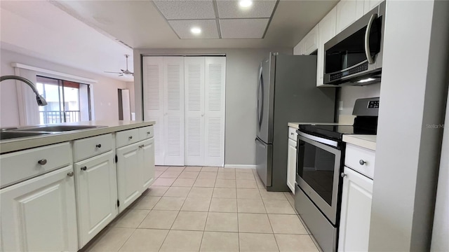 kitchen featuring stainless steel appliances, a sink, white cabinets, recessed lighting, and light tile patterned floors