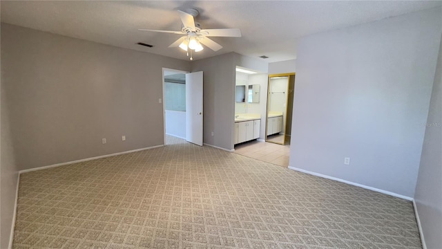 empty room featuring ceiling fan, light colored carpet, and baseboards