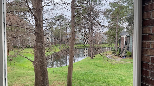 view of green lawn featuring a water view
