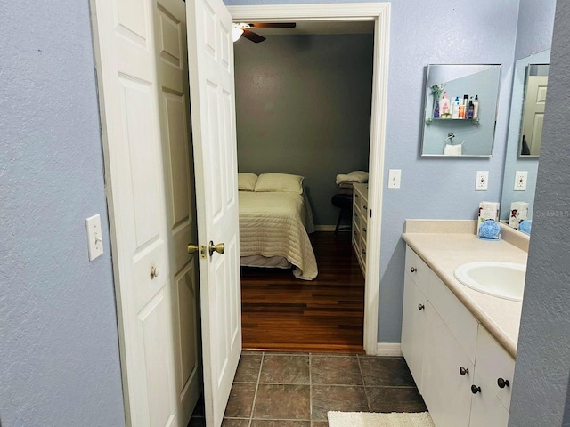 ensuite bathroom featuring vanity, a ceiling fan, baseboards, and a textured wall
