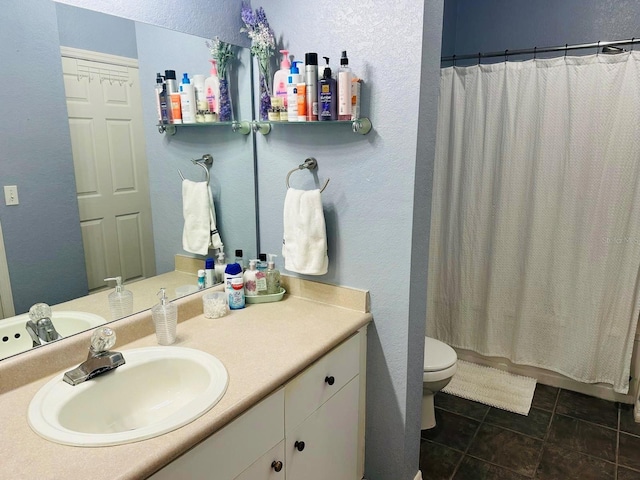 full bathroom featuring vanity, toilet, a textured wall, and tile patterned flooring