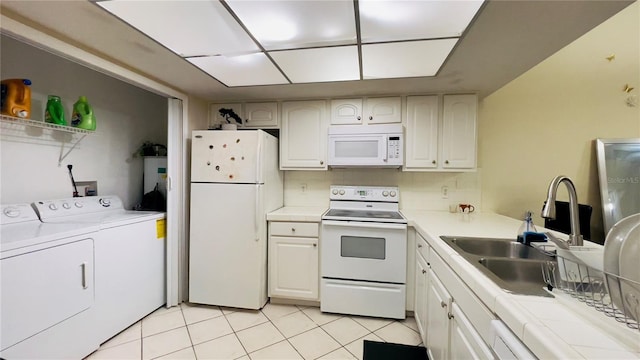 kitchen with white appliances, washing machine and dryer, a sink, light tile patterned floors, and white cabinets