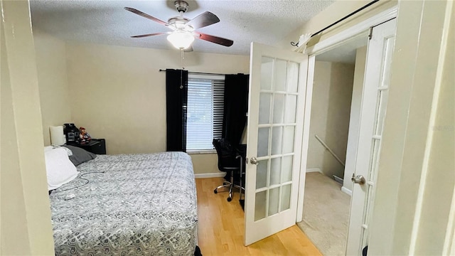 bedroom with a textured ceiling, wood finished floors, ceiling fan, and baseboards