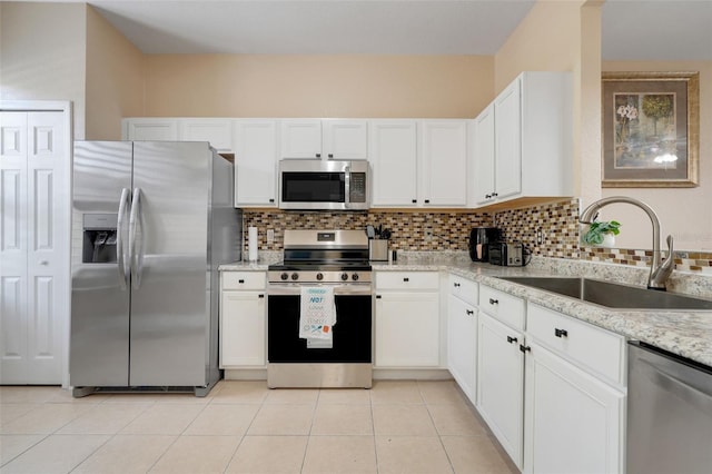 3938 Calabria Ave, Davenport, FL 33897 - kitchen with appliances with stainless steel finishes, a sink, tasteful backsplash, white cabinetry, and light stone counters