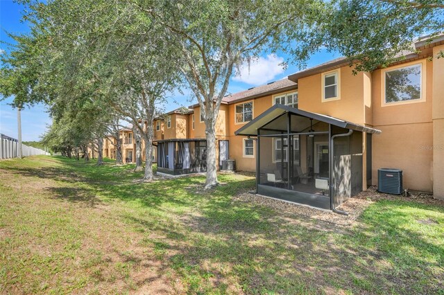 3938 Calabria Ave, Davenport, FL 33897 - back of house with a sunroom, central AC unit, stucco siding, and a yard