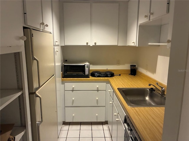 116 Oakmont Ln, New Smyrna Beach, FL 32168 - kitchen with a sink, freestanding refrigerator, white cabinetry, and light tile patterned floors