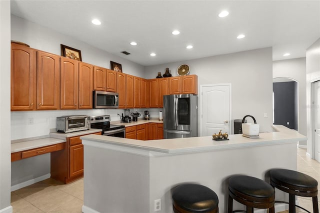 2359 Baronsmede Ct, Winter Garden, FL 34787 - kitchen with stainless steel appliances, a kitchen bar, light tile patterned floors, recessed lighting, and light countertops