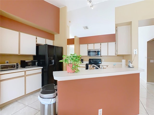 2314 Cormorant St, Kissimmee, FL 34743 - kitchen with black appliances, light tile patterned floors, light countertops, high vaulted ceiling, and white cabinetry