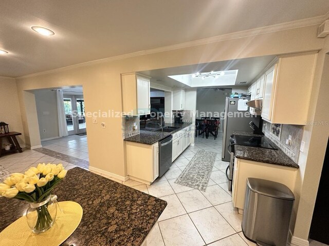 7011 Archwood Dr, Orlando, FL 32819 - kitchen featuring appliances with stainless steel finishes, crown molding, tasteful backsplash, white cabinets, and a sink