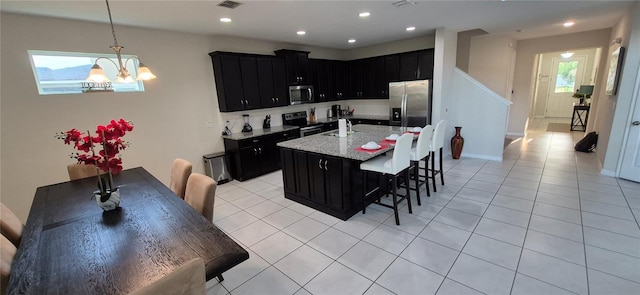 1544 Nassau Point Trl, Kissimmee, FL 34747 - kitchen with stainless steel appliances, dark cabinets, a sink, a breakfast bar, and recessed lighting