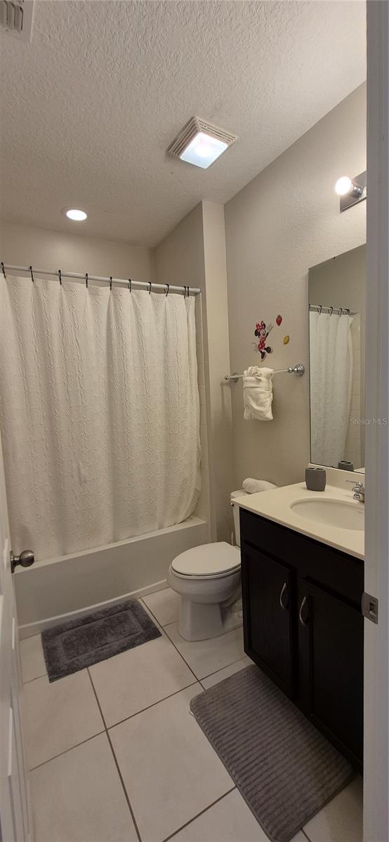 1544 Nassau Point Trl, Kissimmee, FL 34747 - bathroom with vanity, shower / bath combo, toilet, a textured ceiling, and tile patterned floors