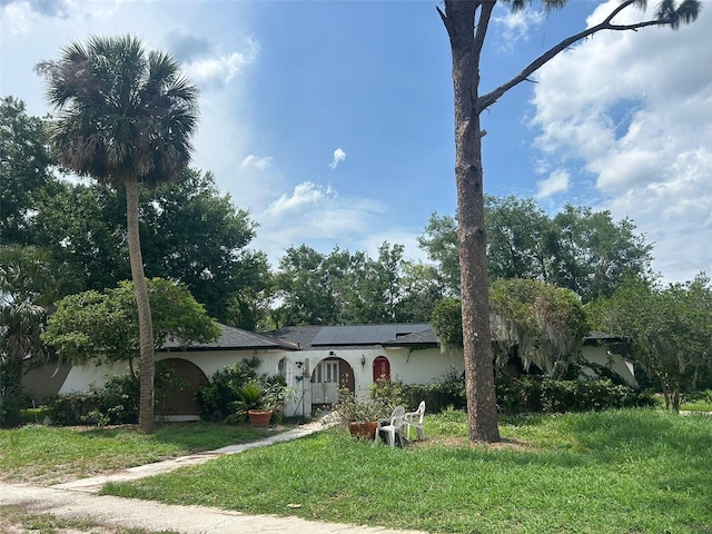 219 Sheridan Ave, Longwood, FL 32750 - single story home featuring roof mounted solar panels, a front lawn, stucco siding, and view of scattered trees