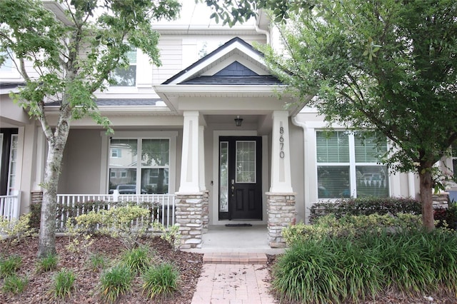 8670 Vedder Ln, Orlando, FL 32832 - view of exterior entry featuring a porch, stucco siding, and stone siding
