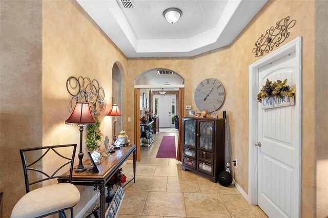 3551 Statham Dr, Apopka, FL 32712 - hallway featuring arched walkways, a textured wall, baseboards, and a tray ceiling