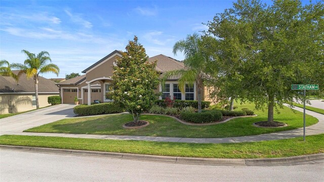 3551 Statham Dr, Apopka, FL 32712 - view of property hidden behind natural elements with driveway, a garage, a front yard, and stucco siding