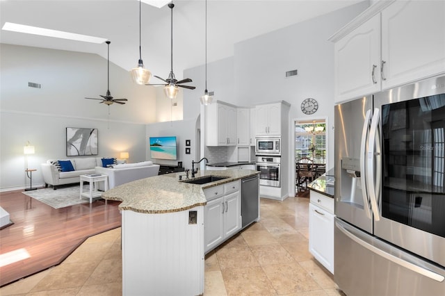 718 Glen Eagle Dr, Winter Springs, FL 32708 - kitchen featuring stainless steel appliances, a sink, high vaulted ceiling, white cabinetry, and light stone countertops