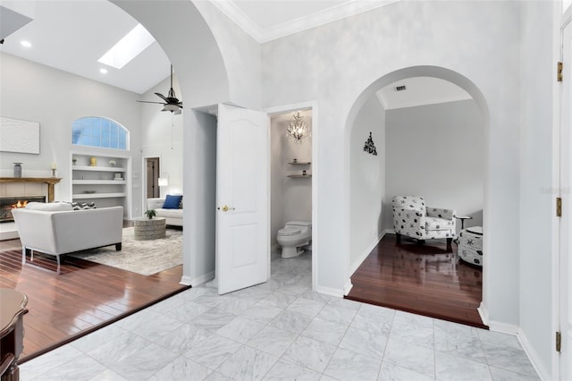 718 Glen Eagle Dr, Winter Springs, FL 32708 - hallway featuring built in shelves, marble look tile flooring, a high ceiling, arched walkways, and baseboards